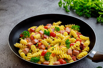 Durum wheat semolina pasta with tomato, green peas in pan.