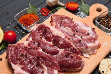 Raw pork meat on wooden cutting board at kitchen table for cooking pork steak roasted or grilled with ingredients herb and spices , Fresh pork