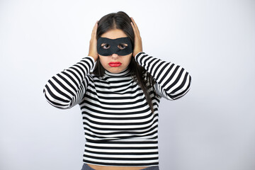 Young beautiful brunette burglar woman wearing mask thinking looking tired and bored with hands on head