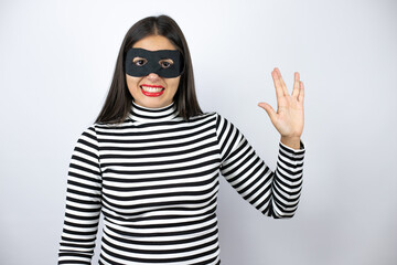 Young beautiful brunette burglar woman wearing mask doing star trek freak symbol