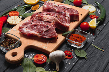 Raw pork meat with spices and vegetables on wooden table