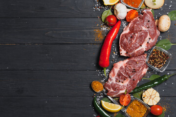 Raw pork meat with spices and vegetables on wooden table