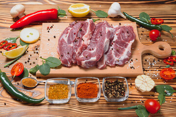 Raw pork meat with spices and vegetables on wooden table