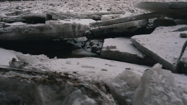 Huge Ice Loads Drift in the River Ogre, Latvia. Stedicam Shot in Snowy Mart Day. Congestion on the River in the Spring. A Large Cluster of Moving Ice Blocks