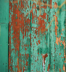 The cracked wooden surface of the wall is a close-up of green color. Old battered background.