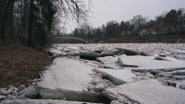 Huge Ice Loads Drift in the River Ogre, Latvia. Static Shot in Snowy Mart Day. Congestion on the River in the Spring. A Large Cluster of Moving Ice Blocks