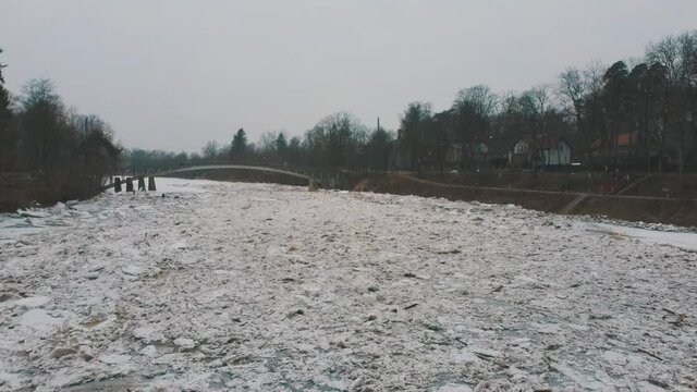 Huge Ice Loads Drift in the River Ogre, Latvia. Aerial Dron Shot in Snowy Mart Day. Congestion on the River in the Spring. A Large Cluster of Moving Ice Blocks