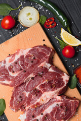 Raw pork meat on wooden cutting board at kitchen table for cooking pork steak roasted or grilled with ingredients herb and spices , Fresh pork