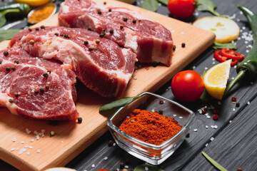 Raw pork meat on wooden cutting board at kitchen table for cooking pork steak roasted or grilled with ingredients herb and spices , Fresh pork