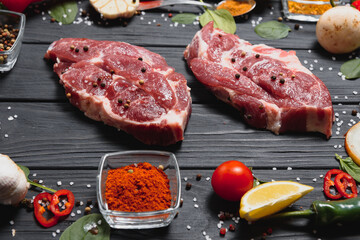 Raw pork meat with spices and vegetables on wooden table