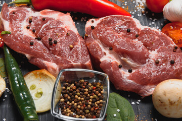 Raw pork meat with spices and vegetables on wooden table