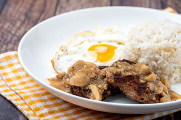 Mushroom Burger Steak Silog (side shot close up)-is a famous Filipino meal that consists of burger steak covered in mushroom gravy sauce, egg and fried rice