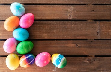 Fototapeta na wymiar Colorful Easter eggs on a wood background with a text / copy space