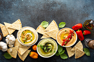Hummus board with garlic, roasted red pepper and basil variety, served with pita overhead view