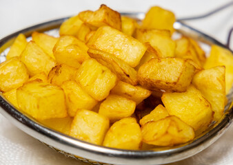 Deep fried potato in a cooling container. Selective focus.