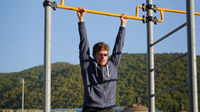 Athlete man doing press exercises and hanging on horizontal bar