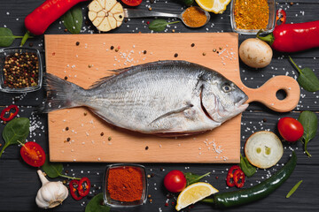 Raw fish cooking and ingredients. Dorado, lemon, herbs and spices. Top view with copy space on table