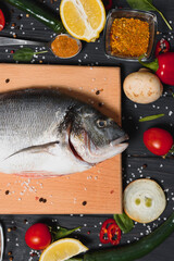 Raw fish cooking and ingredients. Dorado, lemon, herbs and spices. Top view with copy space on table