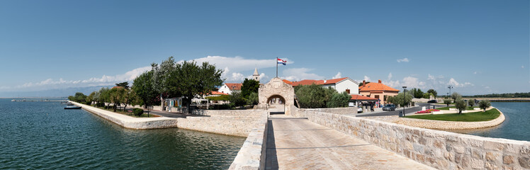 Panoramic image of Nin, historic medieval town in the Zadar County of Croatia. Panoramic image of bridge that leads to city center in lagoon on the Adriatic Sea.
