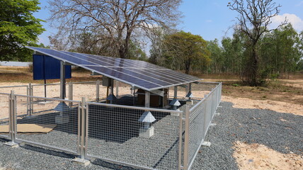 Solar panels and fences. Clean energy panel for electricity generation with metal fence anti-theft in rural area on green plant background with copy space. Selective focus