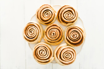 Flat lay of seven delicious cinnamon rolls placed on a cake stand