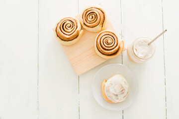 Flat lay of tasty glazed sweet rolls with a cold latte