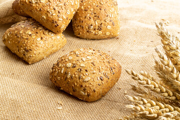 Rustic rye. Fresh loaf of rustic traditional bread with wheat grain ear or spike plant on linen texture background. Bakery with crusty loaves and crumbs. Design element for bakery product label.