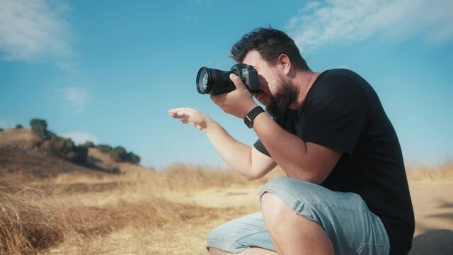 Professional photographer focused on taking pictures in nature park. Slow motion handsome man directing models in outdoor photoshoot. Photography business commercial shot 4K, photographer career