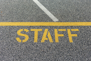 Staff parking sign stenciled on parking lot asphalt.