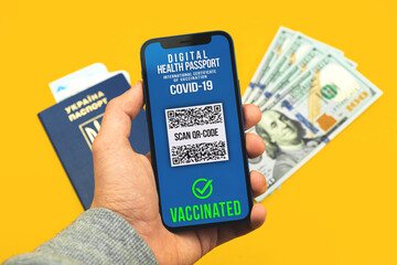 Person holds modile phone with valid digital vaccination passport app, documents for travelers, concept for COVID-19 pandemic