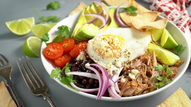 Breakfast burrito bowl with pork carnitas, tomato, beans and rice