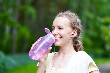 Fitness woman drinking water after running training in summer park