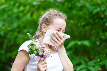 Pollen allergy, womansneezing with bouquet of flowers. Concept: seasonal allergy.