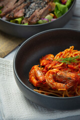 spaghetti with shrimps in tomato sauce on white wooden  background