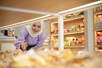 muslim business owner checking her product on the display in the shop. beautiful young entrepreneur