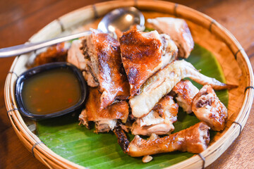 Grilled chicken Thai food with chili sauce on banana leaf and wooden background - Thai traditional menu