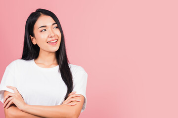Obraz premium Asian happy portrait beautiful cute young woman standing her smile confidence with crossed arms isolated, studio shot on pink background and copy space, Thai female looking to side away