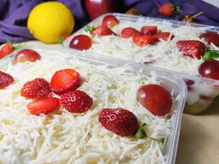Fruit salad with cheese in plastic container. Multi-colored ripe fruits. lemon, apple, lychee, strawberry and grape.  