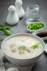 congee with minced pork in bowl on old dark background