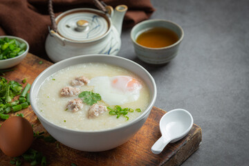 congee with minced pork in bowl on old dark background
