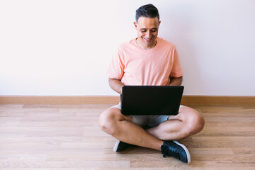 Man sitting on the floor with his laptop telecommuting from home