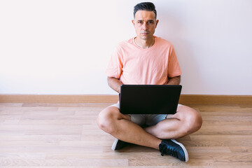 Man sitting on the floor with his laptop telecommuting from home