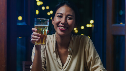 Young Asia lady drinking beer having fun happy night party New Year event online celebration via video call by phone at home at night. Social distance, quarantine for coronavirus. Point of view or POV