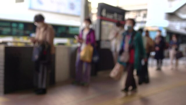 Blurred people with mask practicing social distancing waiting for bus in line at bus station in Hiroshima city, Japan. 4K. March 8, 2021. 