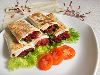 Kebab on White Plate. A delicious Kebab wrap with spicy meat, lettuce, tomato, and sauce. Selective Focus