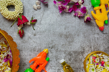 Thai traditional jasmine garland and Colorful flower in water bowls decorating and perfume, marly limestone, plastic water gun on table