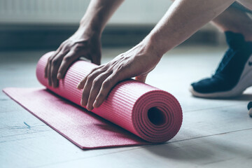 Sporty man is preparing the floor for the pilates session using a special carpet at home