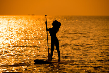Silhouette sport girl stand up paddling on sup board or surfboard enjoy to play extreme sport on...