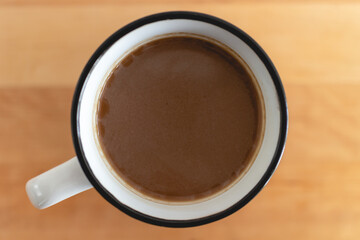 Top view of white cup of hot coffee on wooden table with empty space.