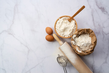 Flour, rolling pins and eggs on a marble background